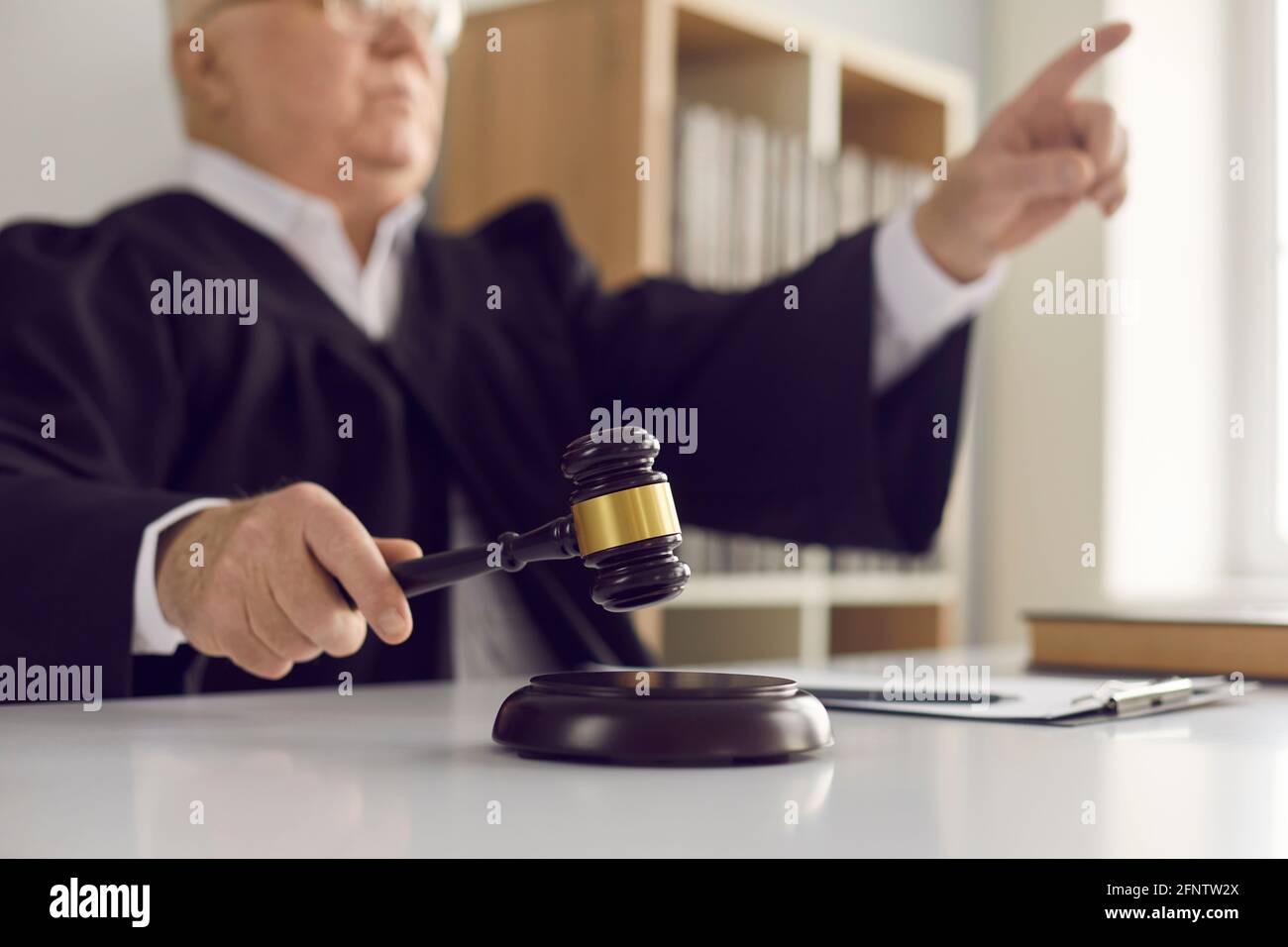 Hammer blow made by a mature judge passing sentence and announcing the closure of the case. Stock Photo