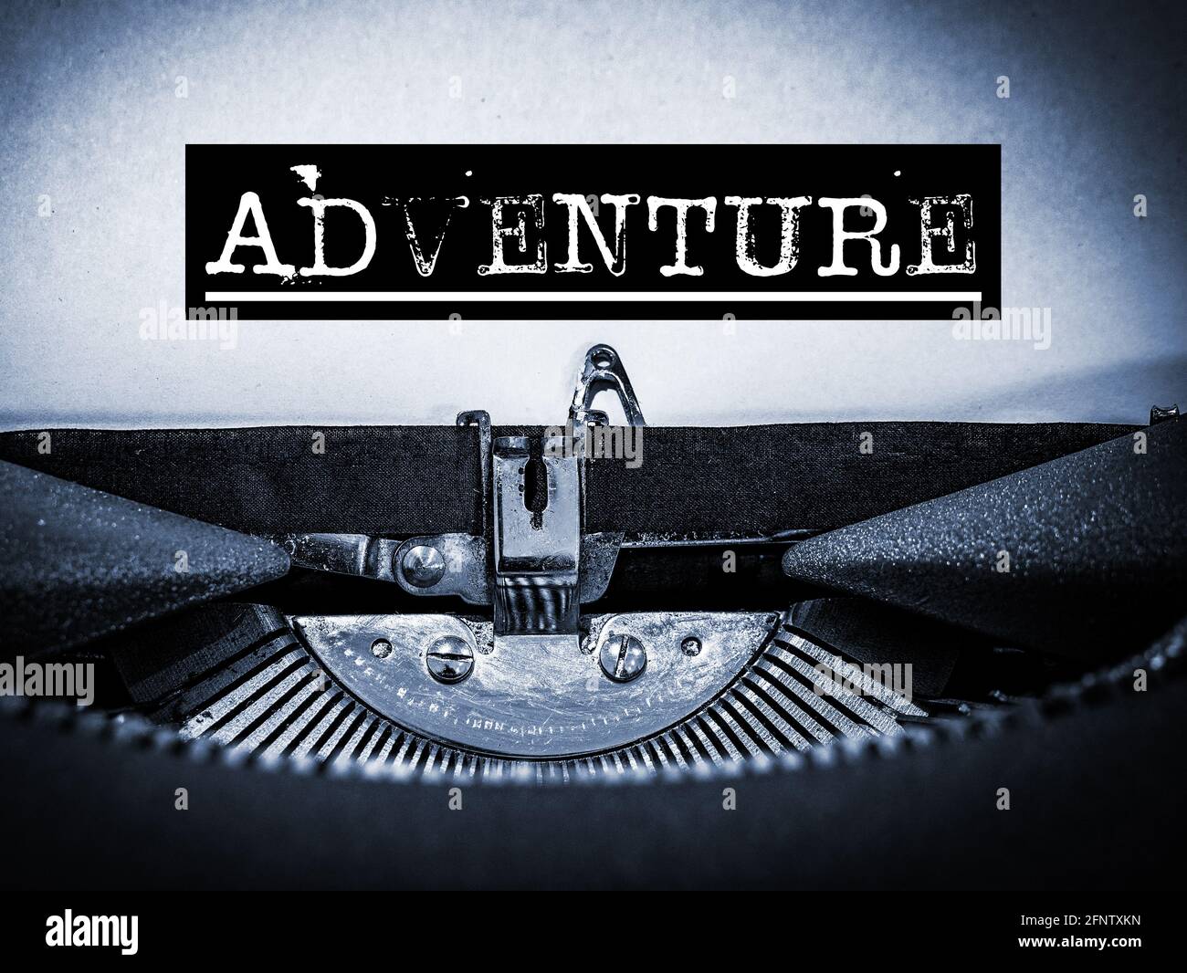 Adventure displayed on a vintage typewriter with underline script and black border in a blue tone Stock Photo
