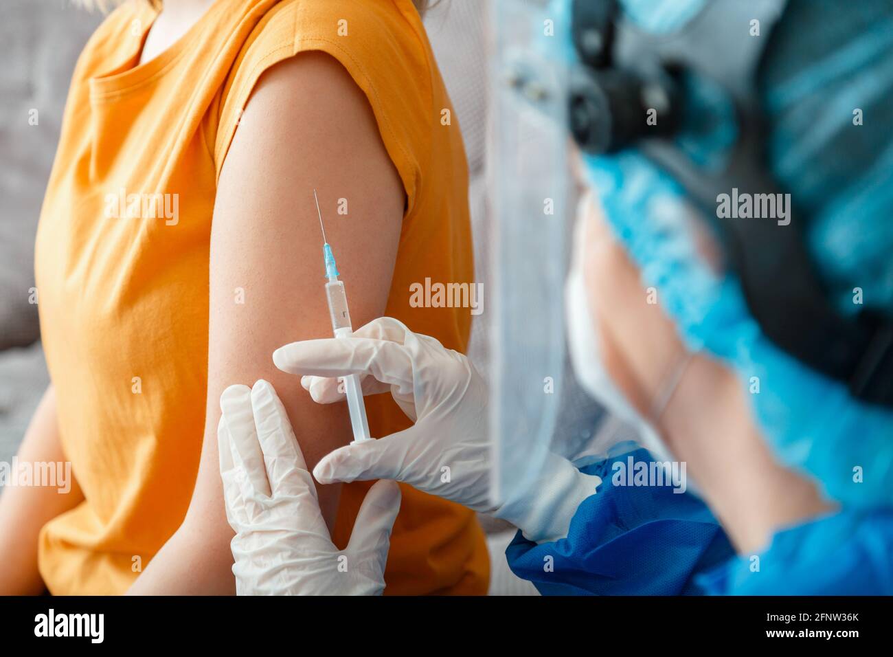 Coronavirus covid 19 vaccine Injection. Nurse in protective medical mask vaccinates woman patient with syringe vaccine in hand. Injection syringe Stock Photo