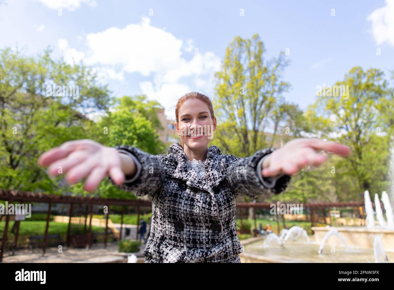 Happy young woman reach out her hands into the camera outdoors in park Stock Photo