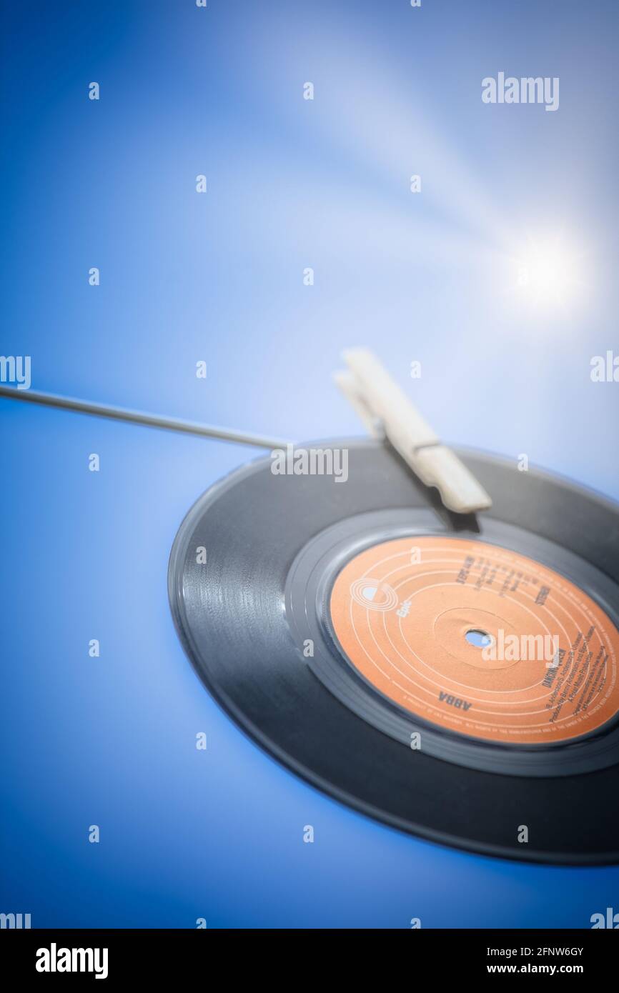 7 inch 45 rpm vinyl record of Dancing Queen by Abba (1976) hanging on washing line in sunlight. Concept of nostalgia, 1970's, entertainment Stock Photo