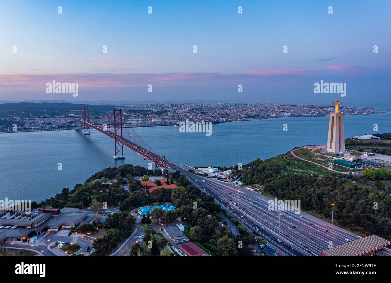 Aerial view of multilane road leading on suspension bridge over Tagus river in twilight time, Lisbon, Portugal. Stock Photo