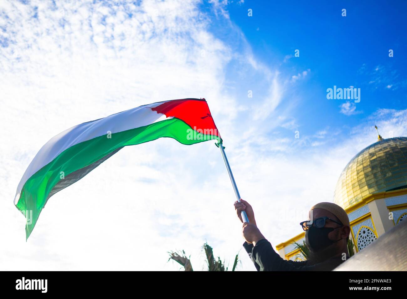 Kendari, Indonesia. 19th May, 2021. A volunteer raises up the Palestinian flag. A fundraising action for the Palestinian community was carried out by the administrators of one of the mosques in the vehicle of the Raudhatul Jannah mosque. This humanitarian appeal was carried out right in front of the Raudhatul Jannah mosque in Kendari city which was a concern for fellow Muslims, the majority of whom were in Palestine. Credit: SOPA Images Limited/Alamy Live News Stock Photo