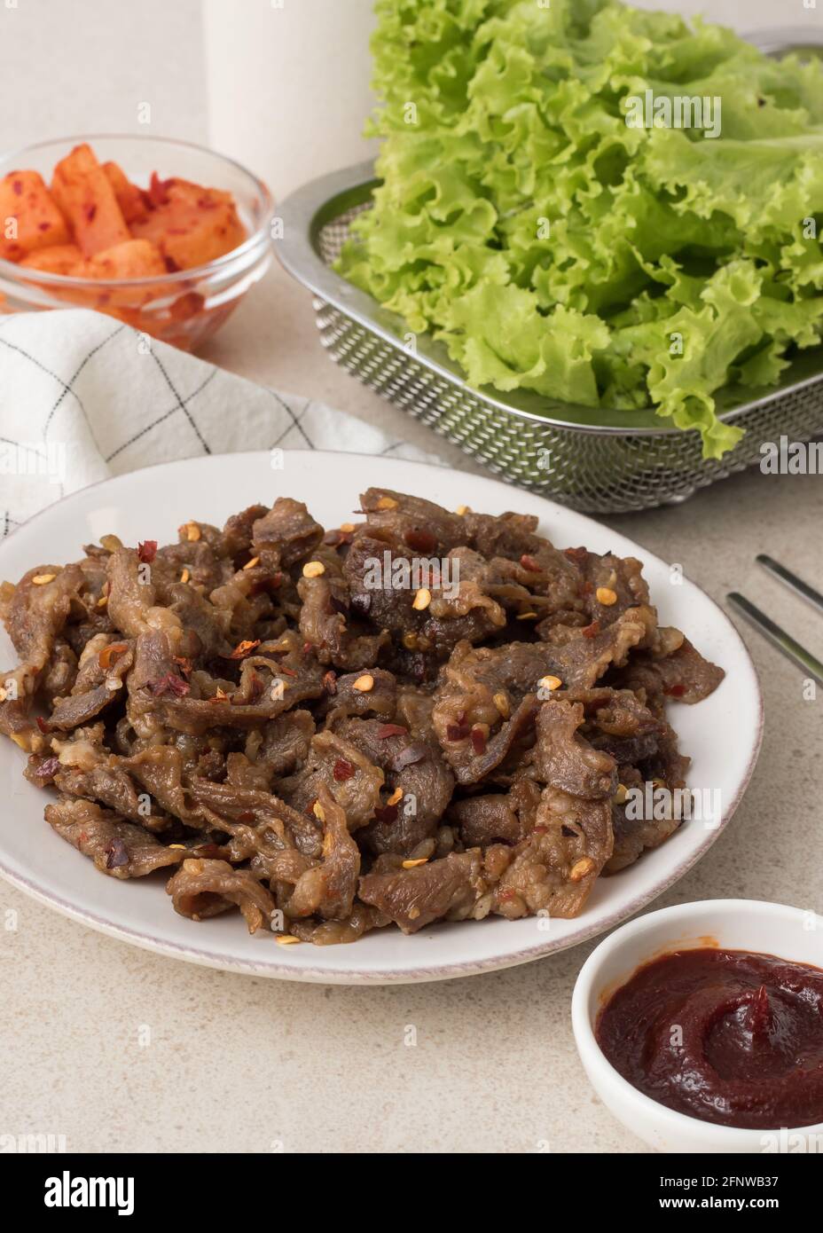 Korean beef bbq samgyeopsal with chili flakes, kimchi radish, lettuce and gochujang dip Stock