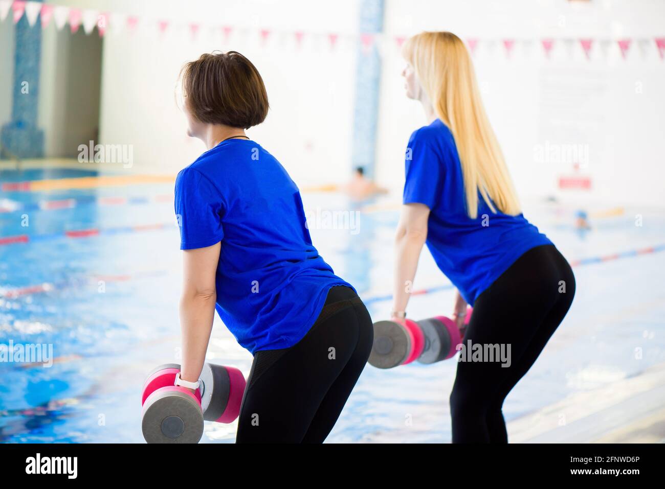 Two erobics trainers show the workout exercises in front of the pool. Stock Photo