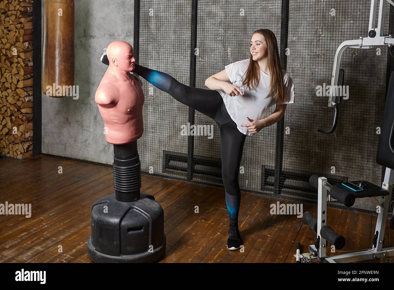 Woman kickboxer kicks bob mannequin punching bag during training in gym Stock Photo Alamy