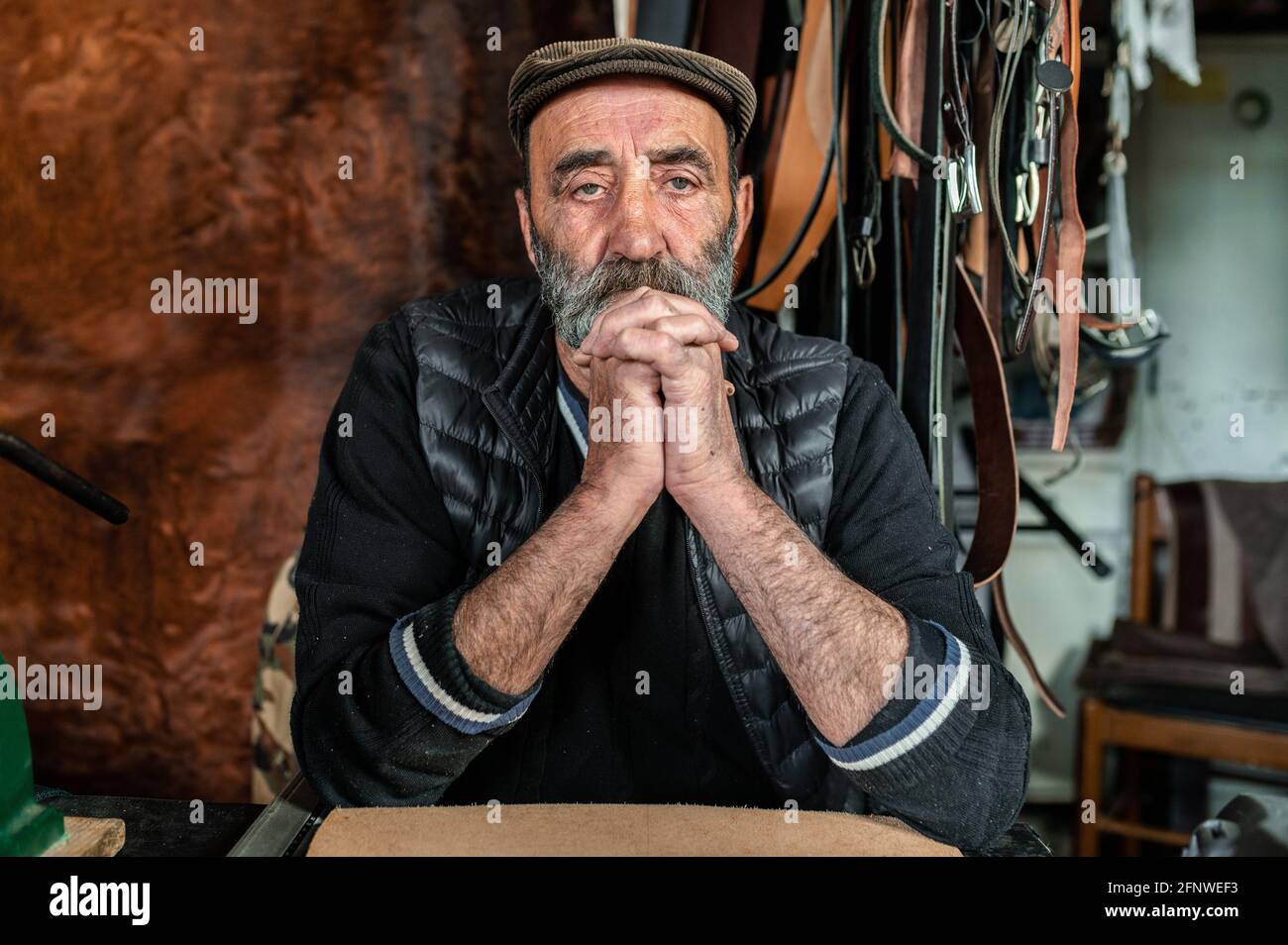 Portrait of old bearded hipster man looking at the camera with serious face. Craftsman working with genuine leather. Stock Photo