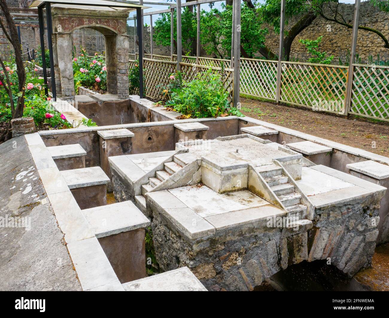 Monumental fountain followed by a small temple and a pond in the garden water canal House of Octavius Quartio - Pompeii archaeological site, Italy Stock Photo