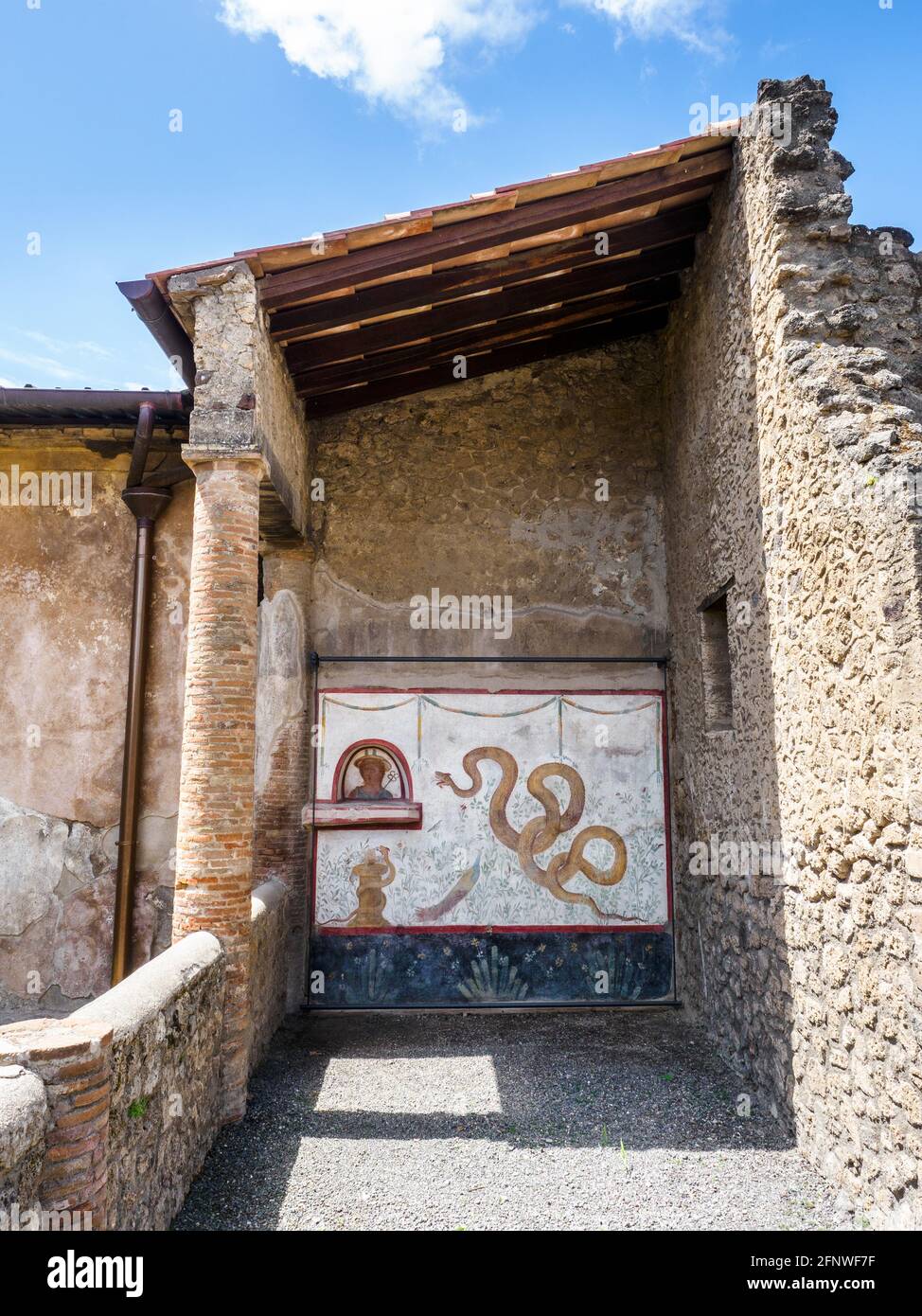 The decoration of the lararium (shrine) shows a large serpent raising its head towards a bust of Mercury set in an arched niche above a projecting ledge Under the niche is a second snake coiled round a small altar. In the background are a variety of plants and bird life including a rather splendid peacock - House of the Cryptoporticus (Casa del Criptoportico)- Pompeii archaeological site, Italy Stock Photo