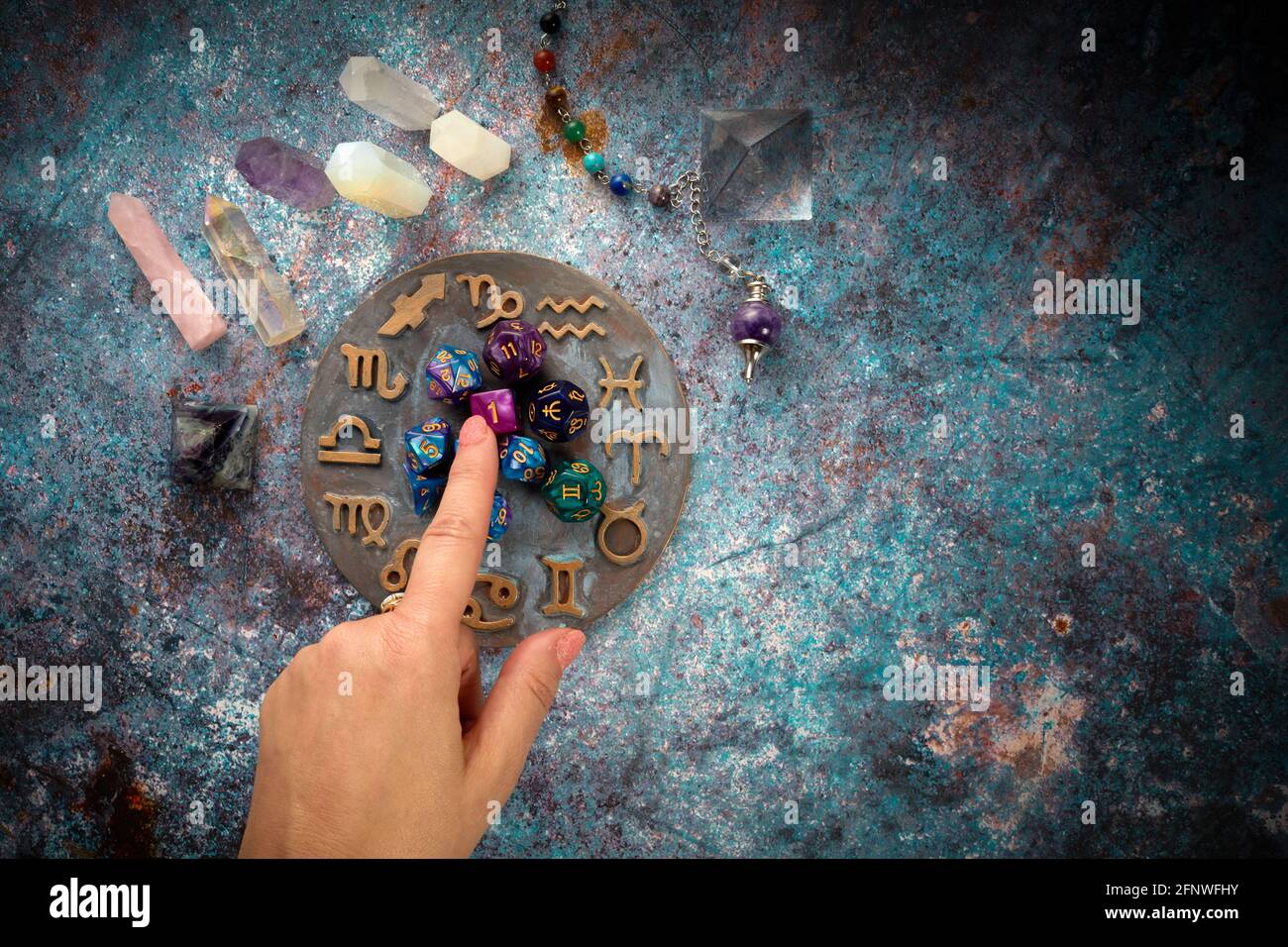 zodiac horoscope symbol with hands and healing crystals on rustic background