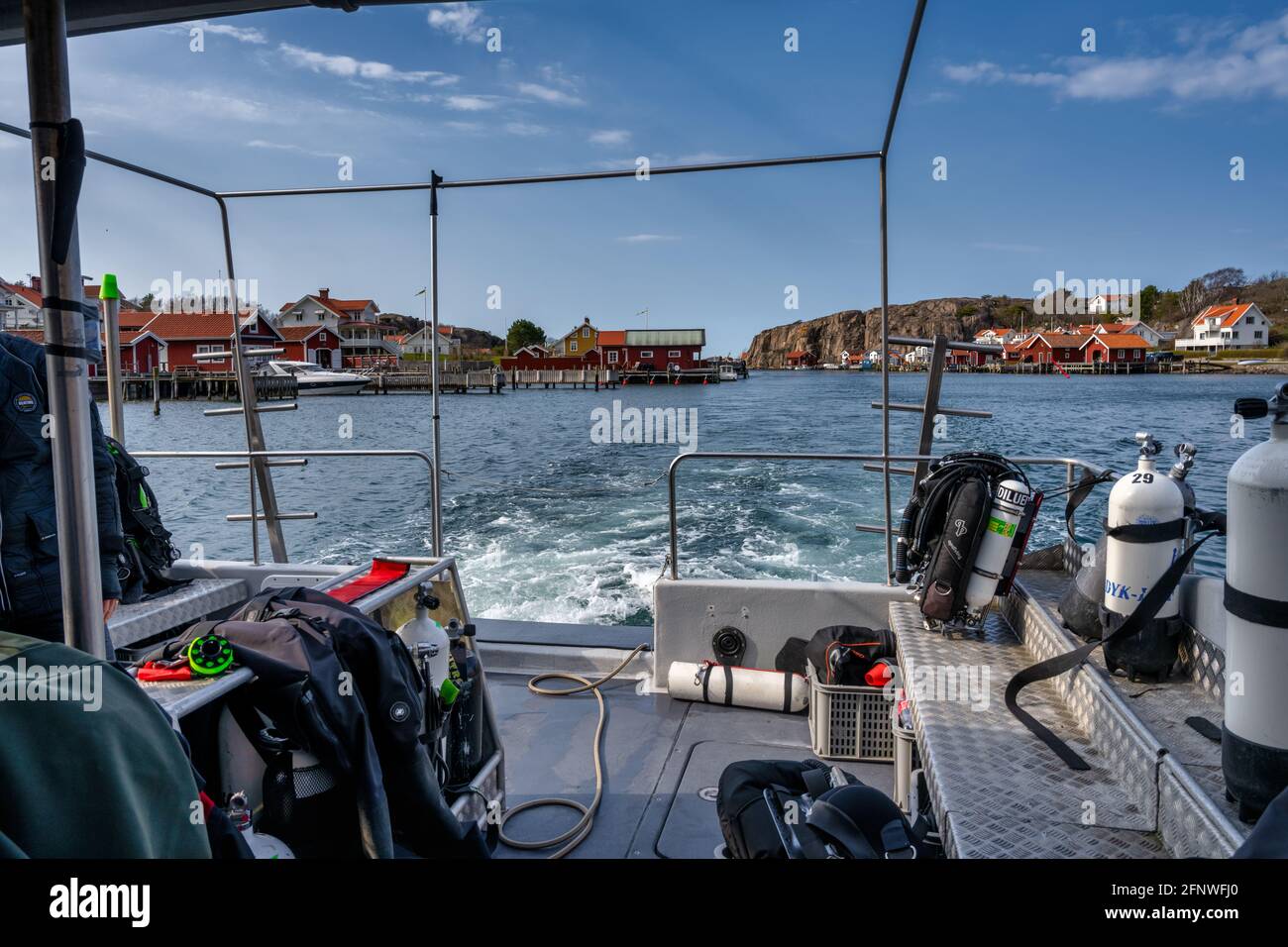 April 17, 2021 - Hamburgsund, Sweden: This picturesque fishing village on the Swedish West coast are seen from the deck of a dive boat. Traditional red sea huts and a blue sky in the background Stock Photo