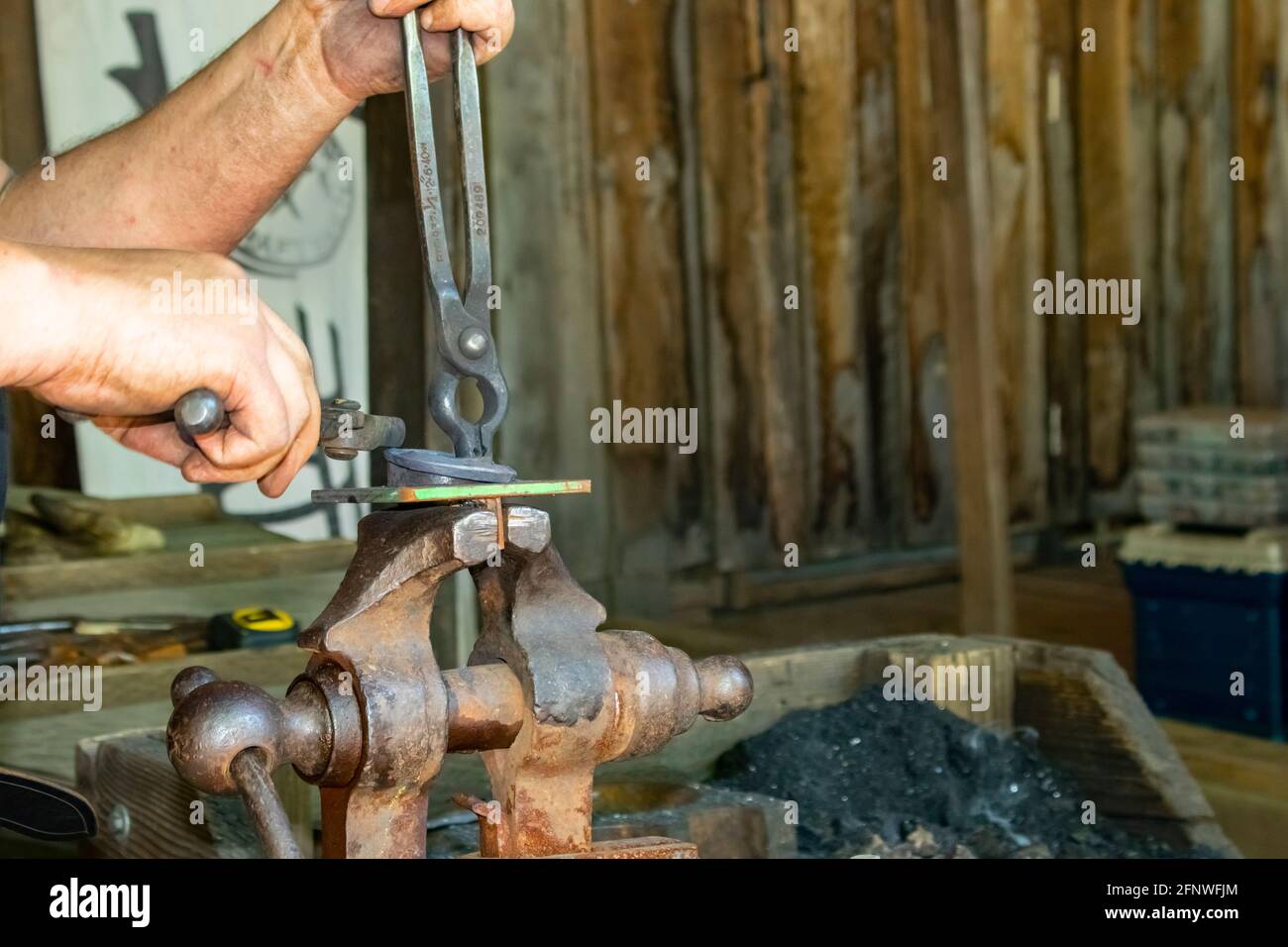 Blacksmith's hands at work at forge working with object held in vise with tongs at Oklahoma Renaissance Festival Muskogee Oklahoma 5 5 2018 Stock Photo