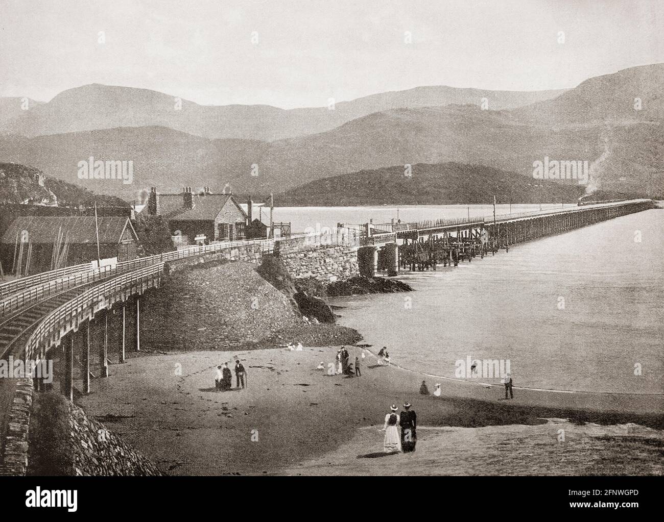 A late 19th Century view of Barmouth Bridge, or Barmouth Viaduct, a single-track wooden railway viaduct across the estuary of the Afon Mawddach near Barmouth, Wales. It is 820 metres (900 yd) long and carries the Cambrian Line. It is the longest timber viaduct in Wales and opened in  1867, one of the oldest in regular use in Britain. Cader Idris mountain can be seen on the far bank. Stock Photo