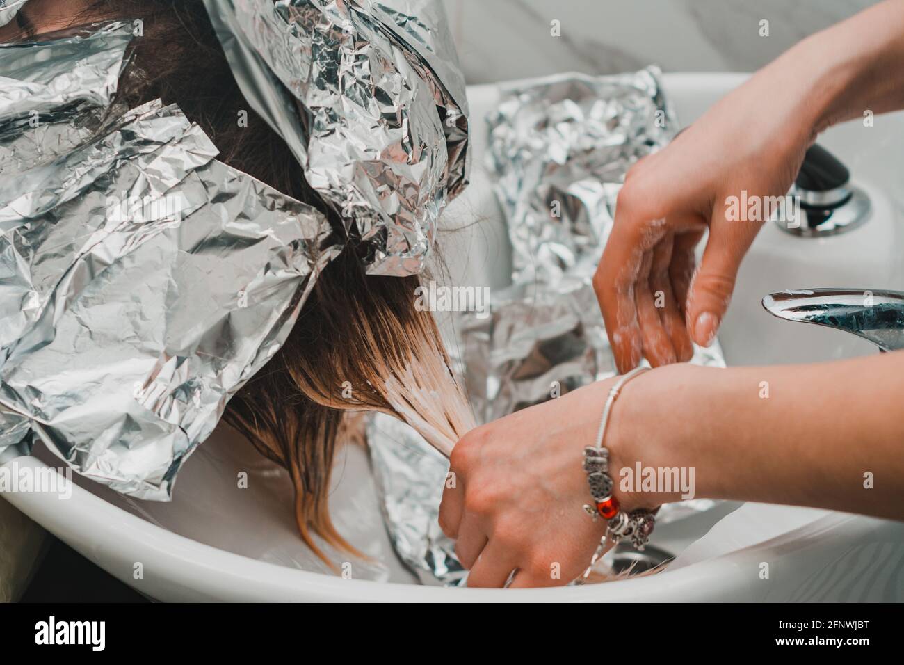 Washing hair dye from a hairdresser, removing foil from hair. new Stock Photo Alamy