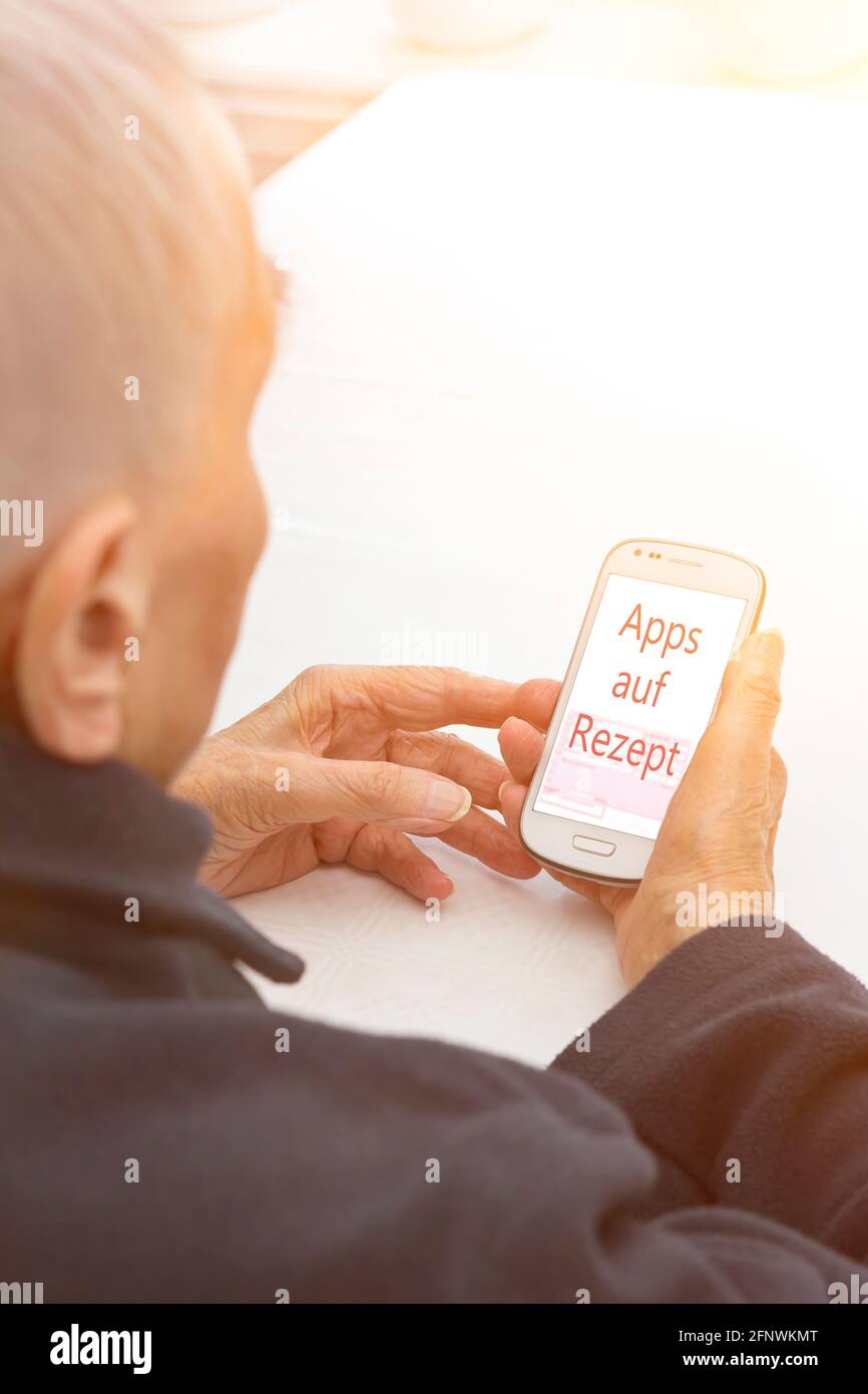 Old woman with a smartphone showing the german text Apps auf Rezept, translation: app on prescription. Stock Photo