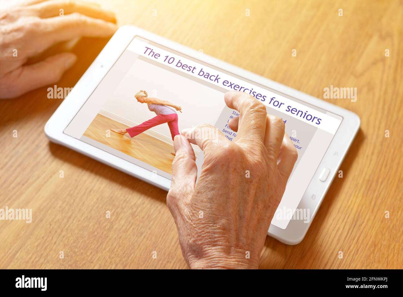 Home fitness concept: hands of a senior woman zooming in on instructions for back exercises on a tablet pc. Stock Photo