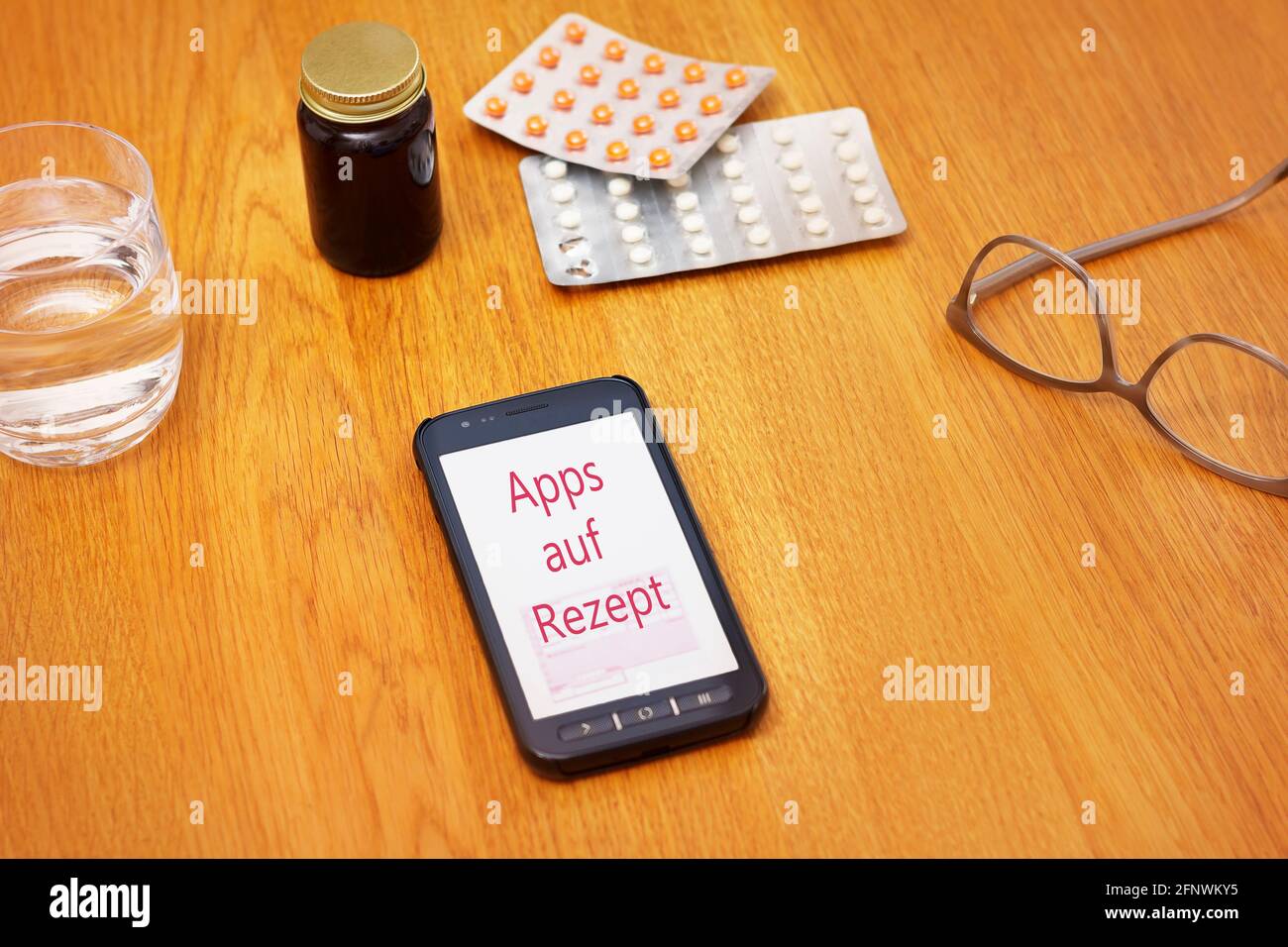 Medicine and smartphone on a table showing the german text: Apps auf Rezept. Translation: apps on prescription. Stock Photo
