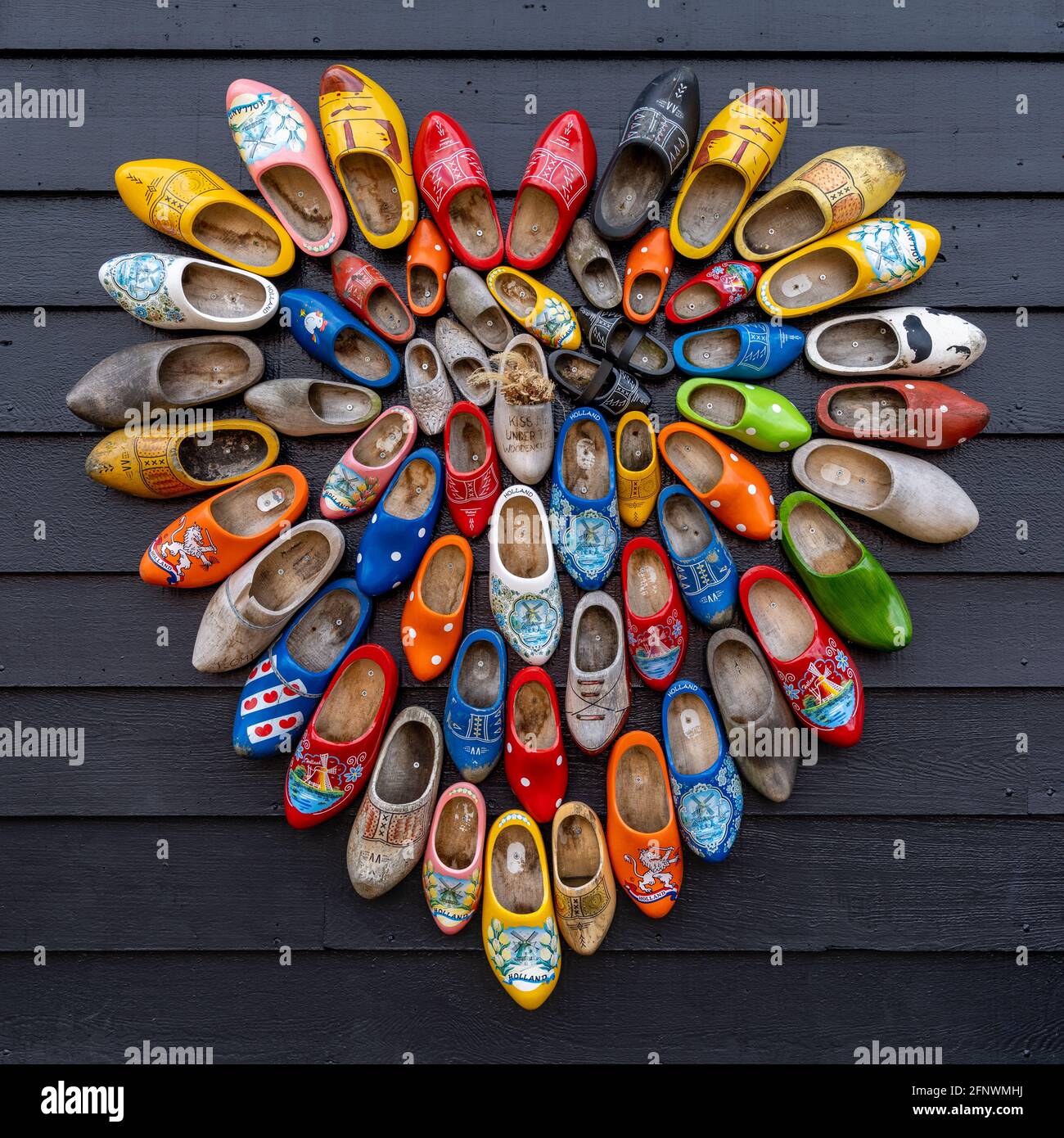 A close up view of many colorful traditional clogs hanging on the wall of a house in the Netherlands Stock Photo