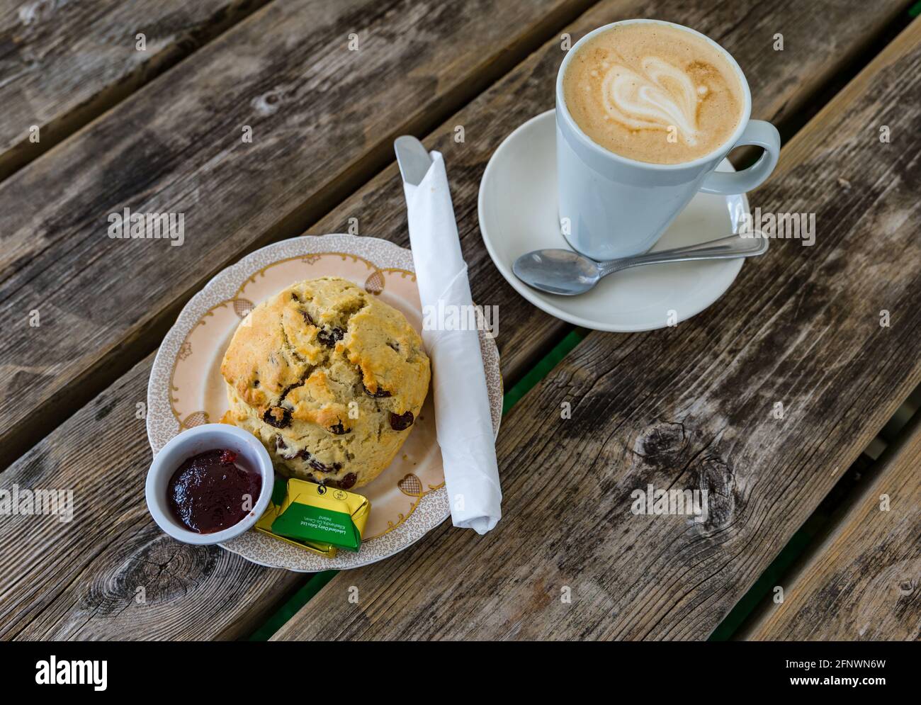 Homemade fruit scone with jam and butter on plate served on outdoor