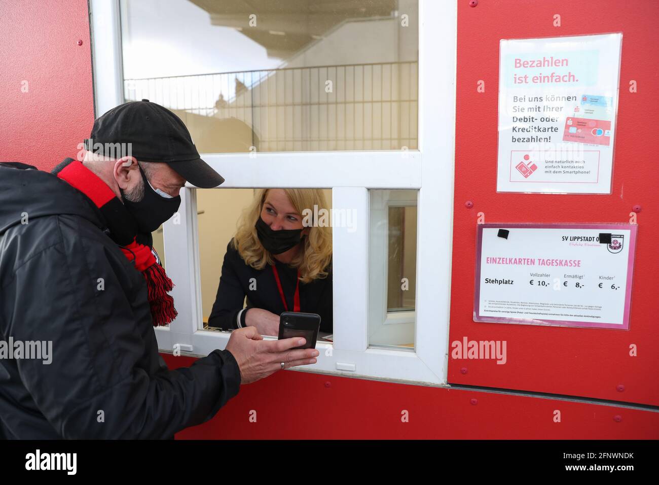 19 May 2021, North Rhine-Westphalia, Lippstadt: A spectator shows the  result of a negative quick test on his mobile phone at a ticket booth in  the Liebelt Arena before the start of