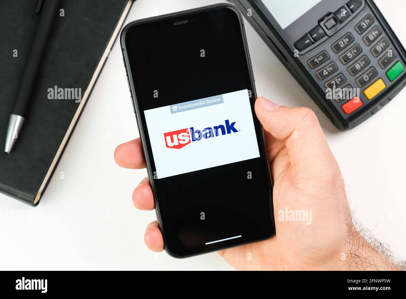 US bank logo on the black smartphone screen in mans hand on the background of payment terminal, May 2021, San Francisco, USA Stock Photo