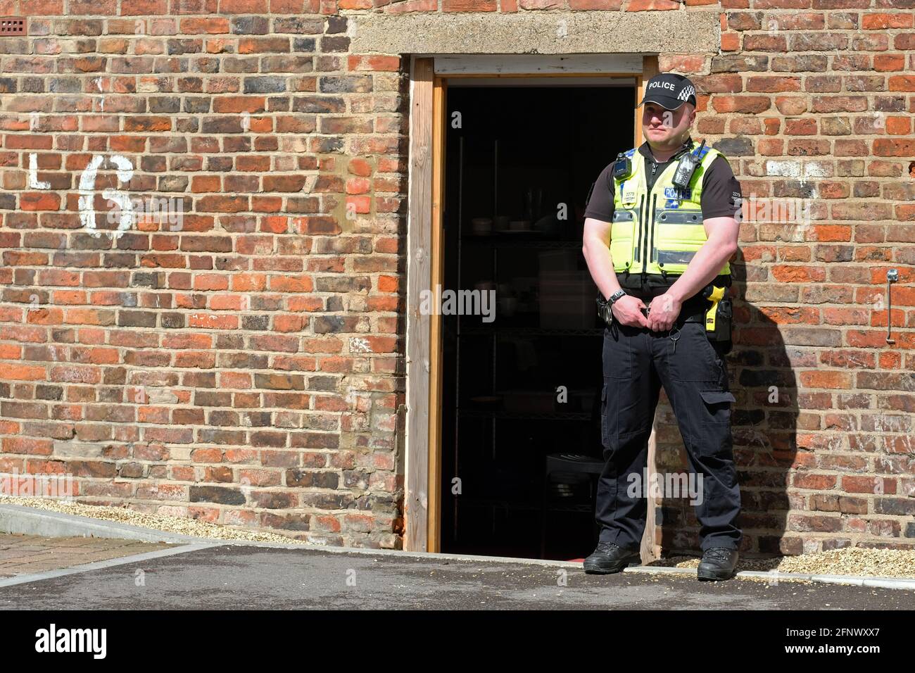 Gloucester, Gloucestershire, UK - Wednesday 19th May 2021 - Police officer stands guard at the rear of the Clean Plate cafe as Police begin excavations in the search for Mary Bastholm who went missing in 1968 aged just 15 years old and who may have been a victim of serial killer Fred West. Photo Steven May / Alamy Live News Stock Photo