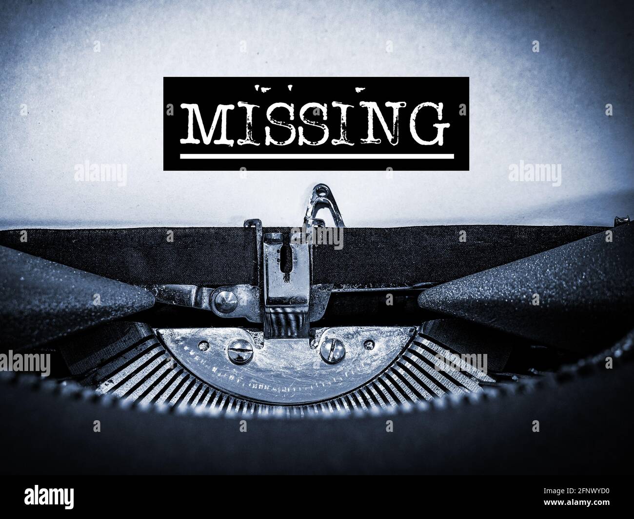 Missing displayed on a vintage typewriter with underline script and black border in a blue tone Stock Photo