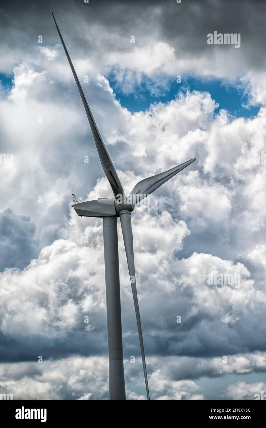 Wind turbine at Penyfan Pond, near Blackwood, South Wales against a dramatic background of rain clouds and blue sky. Stock Photo