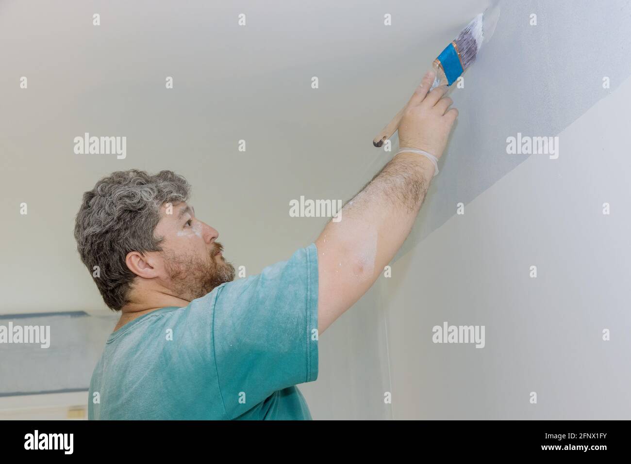 Professional painter using a brush to paint on wall Stock Photo