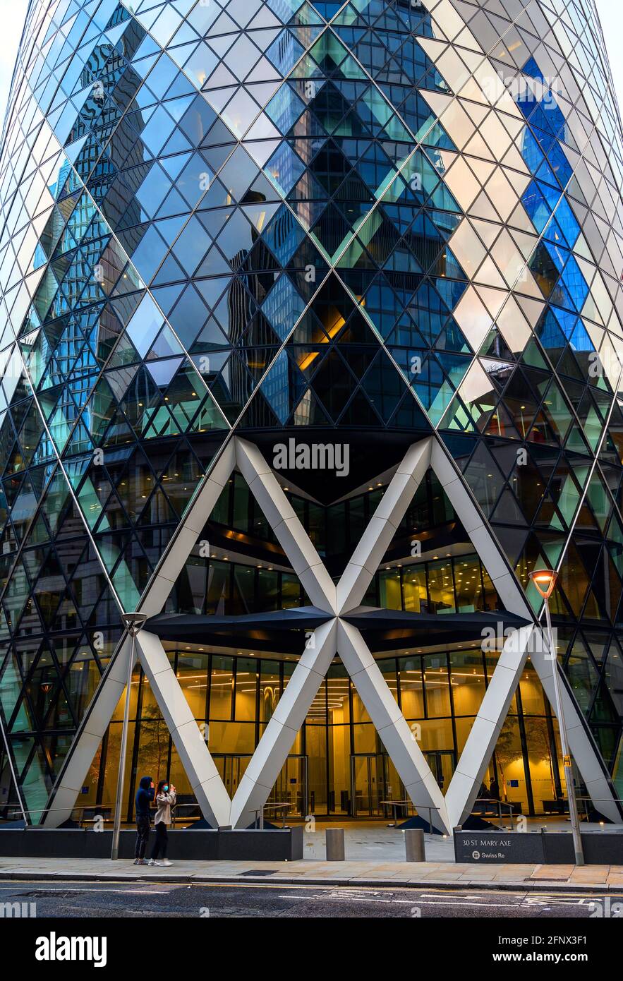 London, UK: Gherkin building in the City of London. View of the entrance of the Gherkin or 30 St Mary Axe with tourists talking photographs. Stock Photo