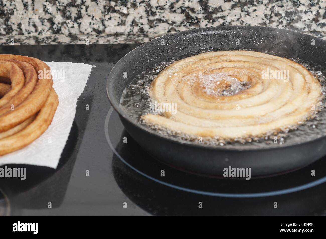 Traditional Spanish churros frying in oil in an iron pan Stock Photo