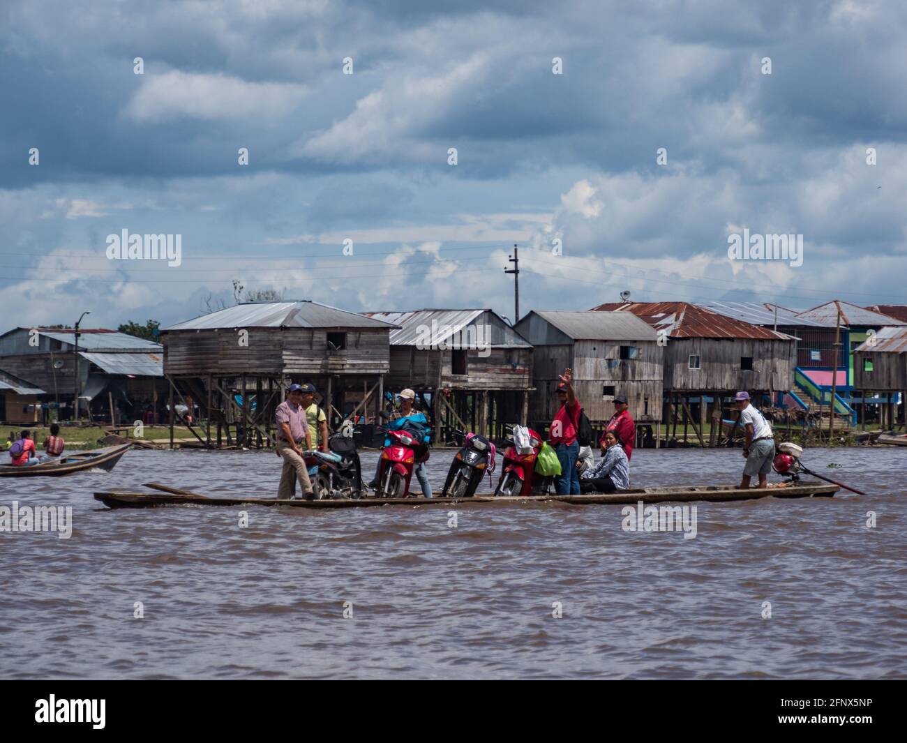 Belen, Dec, 2019: Transportation of motorcycles on a wooden boat. In the background floating houses in the floodplain of the Itaya River, the poorest Stock Photo