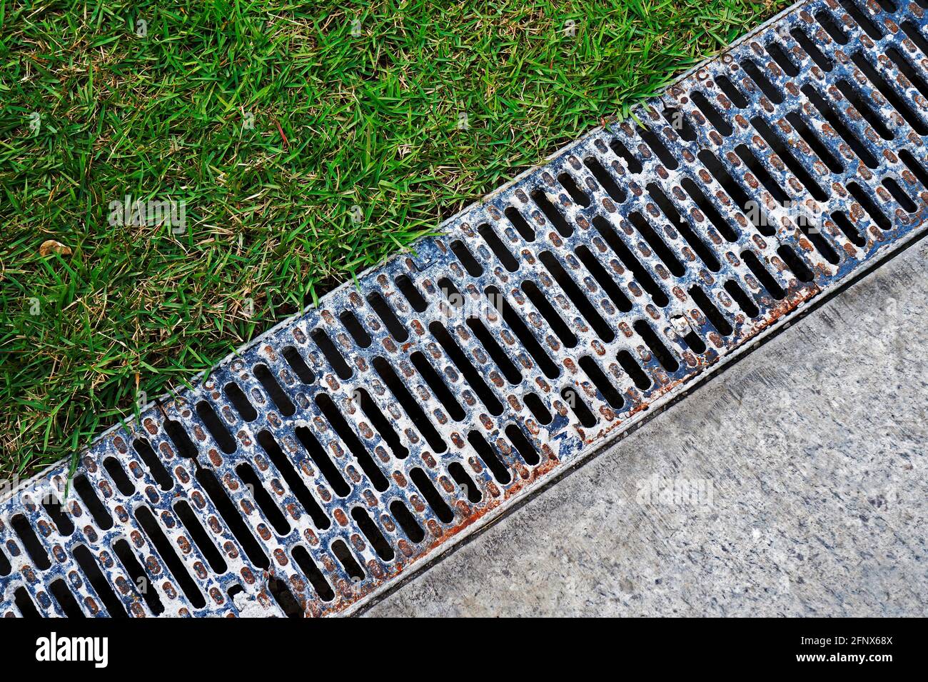 Drain water between sidewalk and garden Stock Photo