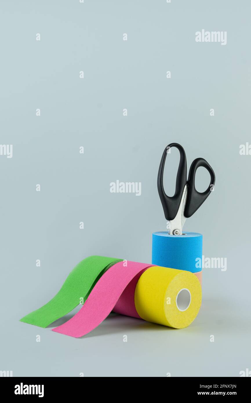 Rolls kinesiology tape for athletes and scissors on blue. Kinesiology