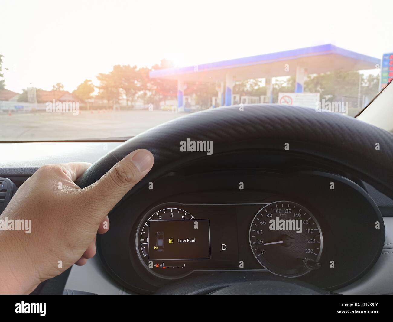 Low fuel gauge displayed in the car causes the driver to drive to the gas station Stock Photo