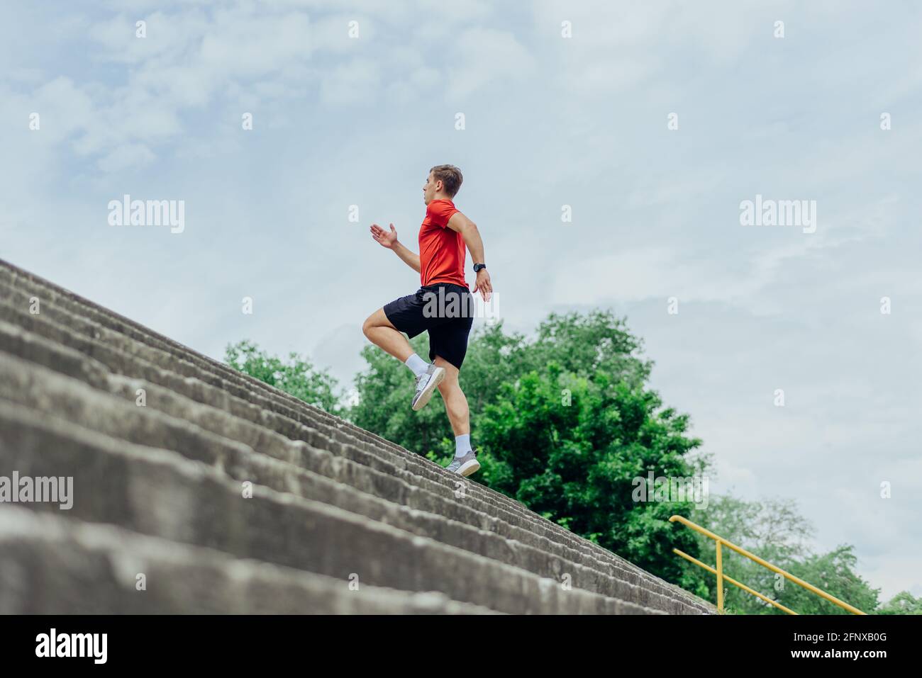 Fit male athlete performing stairs workout, running up climbing stairs