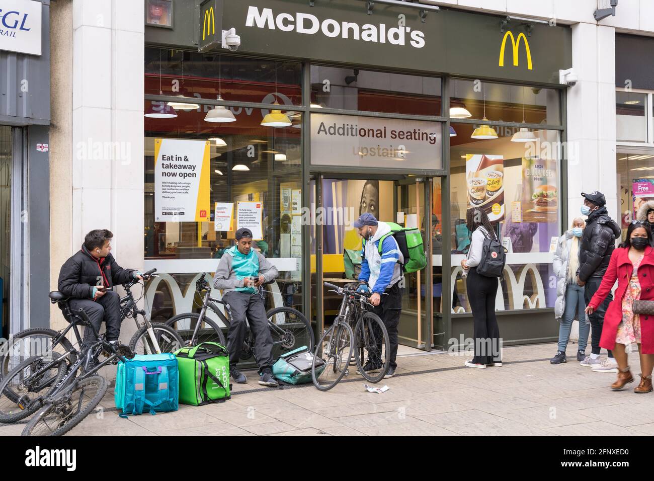 customers and couriers Deliveroo man queue outside McDonald's restaurant in Cutty Sark, Greenwich, London England food delivery UK Stock Photo
