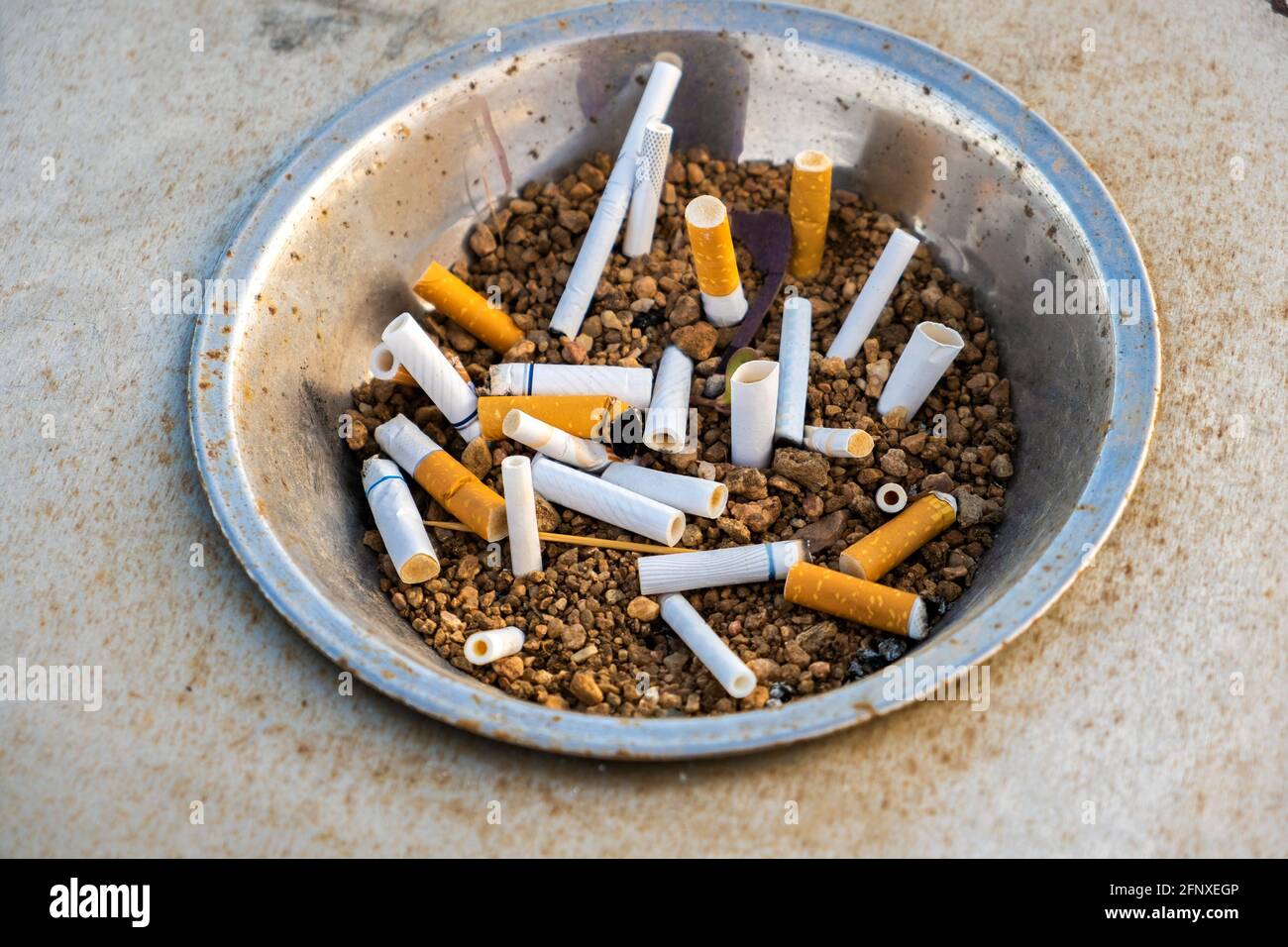 Close up of cigarettes butts in metal ashtray on street. Concept of many cigarette debris after smoking. Stock Photo