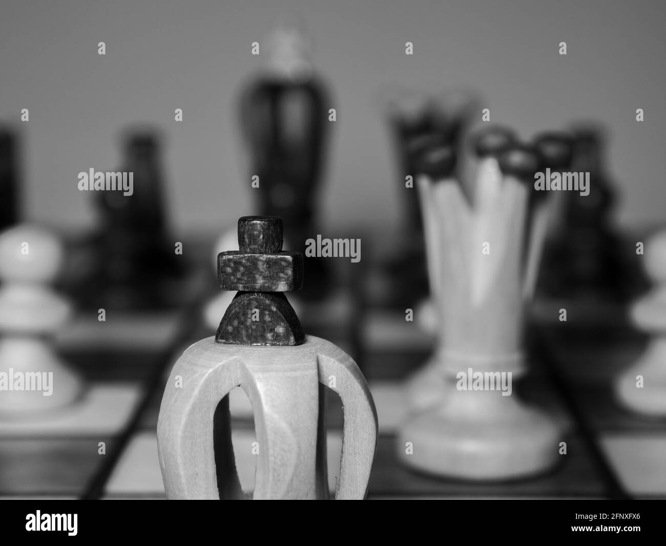 Chess pieces. A close-up on the king and queen chess pieces. Black and white photography. Shallow depth of field. Blurry figures in the background. Stock Photo
