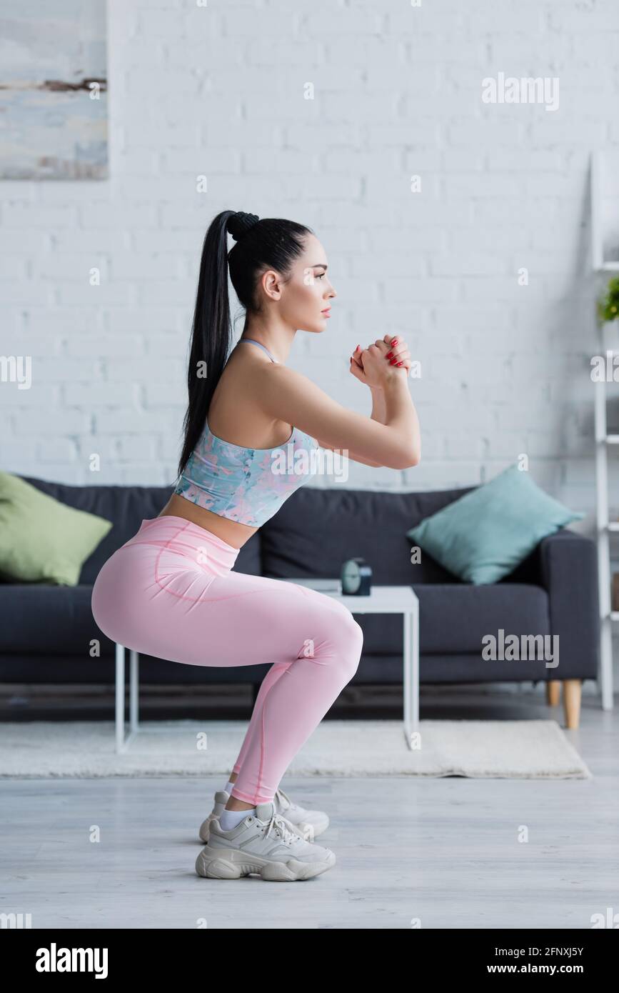 side view of brunette woman in sportswear exercising in awkward pose ...