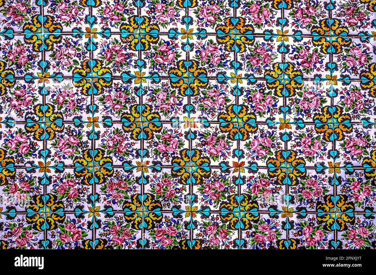 Colorful background with a bright floral pattern assembled from painted ceramic tiles on  the wall of the Golestan Palace Stock Photo