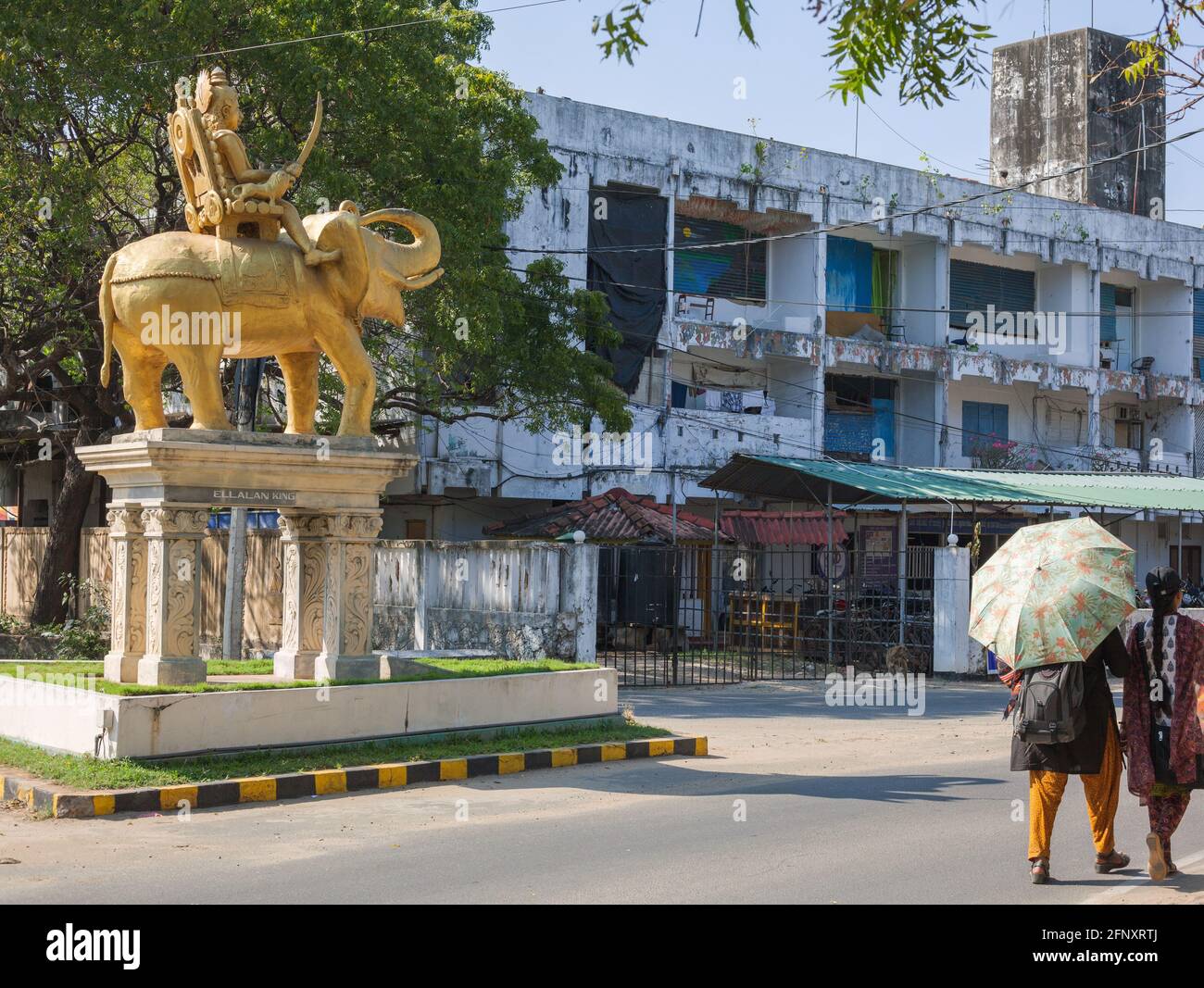 Sri Lankan pedestrians pass one of Shirparsariyar Chidamabarampillai's golden tamil king statues created in 2014, Jaffna, Northern Province, Sri Lanka Stock Photo