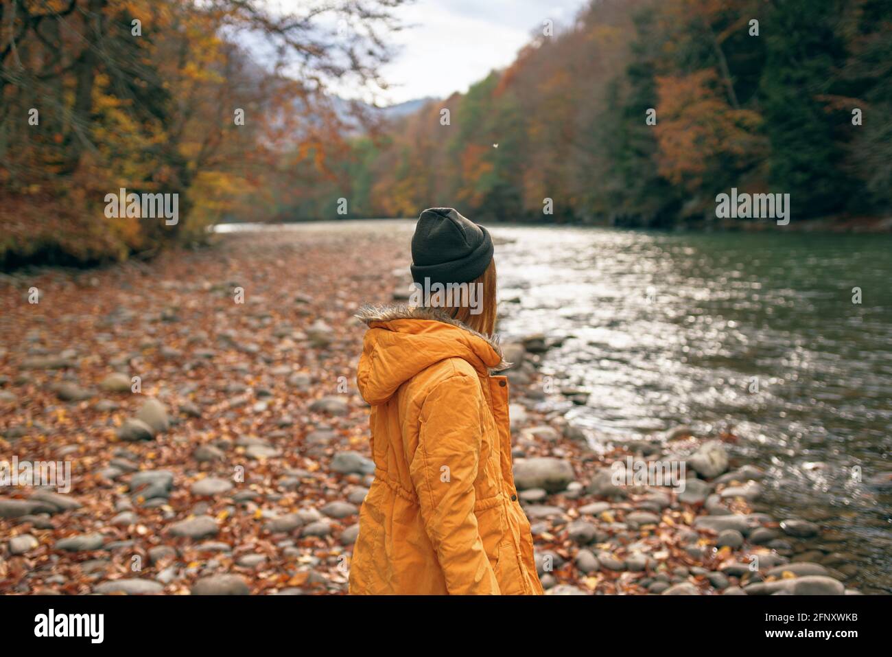 woman walks along the river Autumn forest nature mountains Stock Photo ...