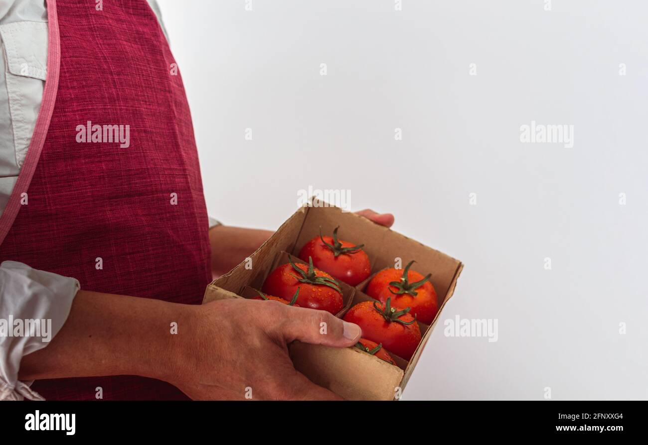 Unrecognizable farmer holding box with fresh tomatoes isolated on a ...