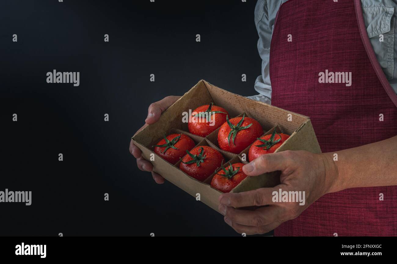 Unrecognizable farmer holding box with fresh tomatoes isolated on a ...