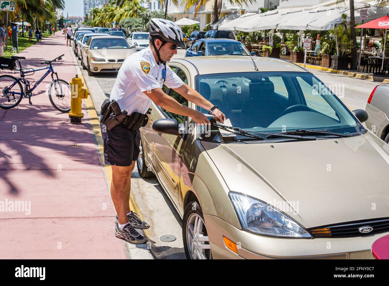 Miami Beach Florida,Ocean Drive,policeman police giving leaving placing parking ticket car window windshield, Stock Photo