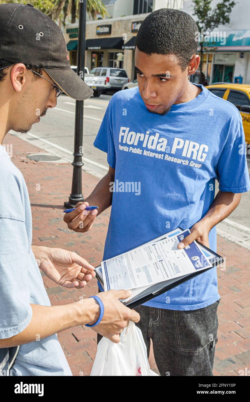 Miami Florida,Coconut Grove teen teenager Black boy male asking,man sign petition PIRG public interest research group,political politics issue issues Stock Photo