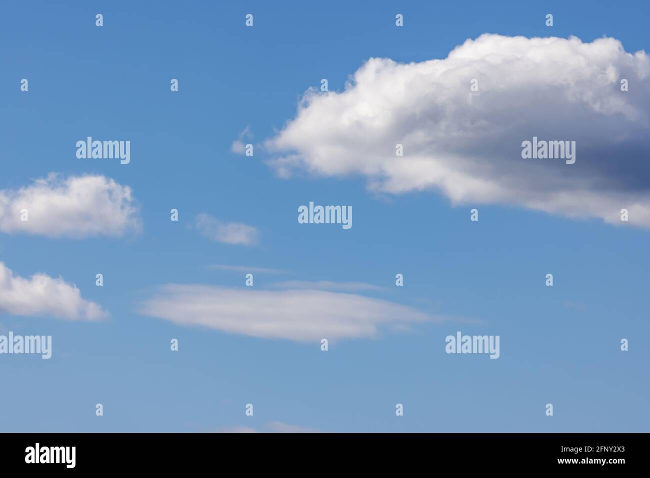 white puffy clouds on a bright blue sky Stock Photo