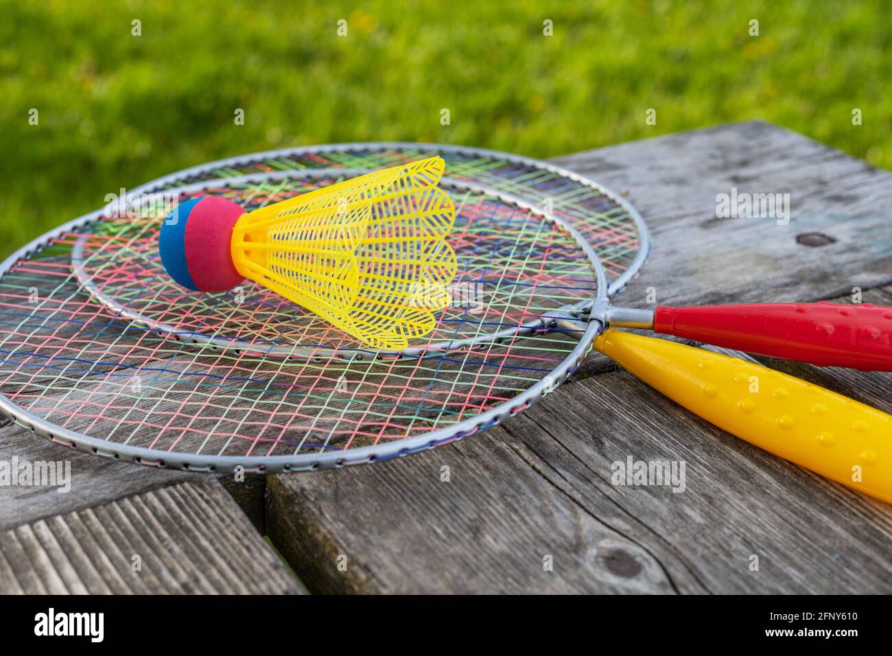 Badminton game rackets and shuttlecock on wooden table with green grass backgroud in the park on a sunny summer day. Active lifestyle concept. Fun out Stock Photo