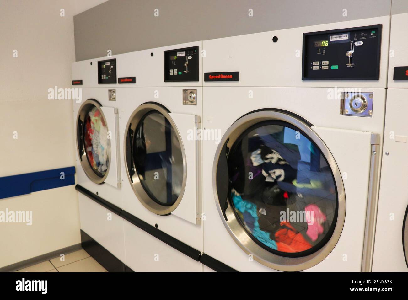Three dryers in a row drying clothes in a laundromat Stock Photo Alamy